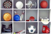 Frontalansicht von Sport-Utensilien in einem weissen Regal. Man sieht eine Zielscheibe, einen Volleyball, eine Hantel, einen Handball, einen Basketball, ein Bowlingball und zwei Kegel, Tischtennisschläger und einen Tischtennisball, ein Rollbrett, Schlittschuhe, einen Tennisschläger mit Tennisball einen Fussball und Boxhandschuhe.   Frontalansicht von Sport-Utensilien in einem weissen Regal. Man sieht eine Zielscheibe, einen Volleyball, eine Hantel, einen Handball, einen Basketball, ein Bowlingball und zwei Kegel, Tischtennisschläger und einen Tischtennisball, ein Rollbrett, Schlittschuhe, einen Tennisschläger mit Tennisball einen Fussball und Boxhandschuhe.